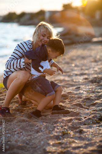Fotografía Beautiful woman with a child of four years playing on the beach near the sea