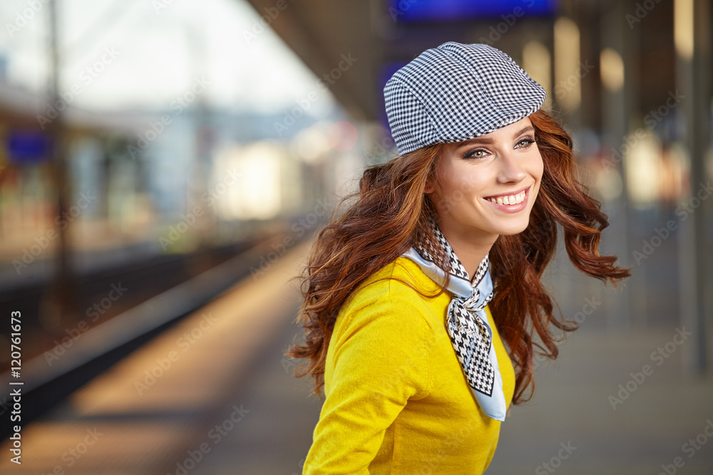 Beautiful young woman with suitcase is waiting a train