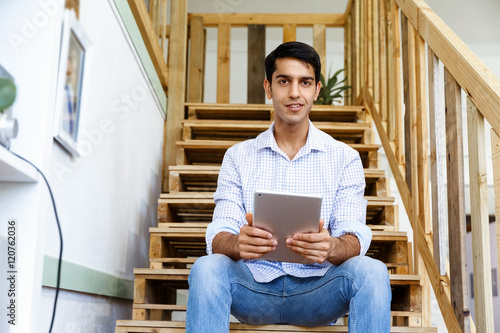 Portrait of young man sitting at the stairs in office