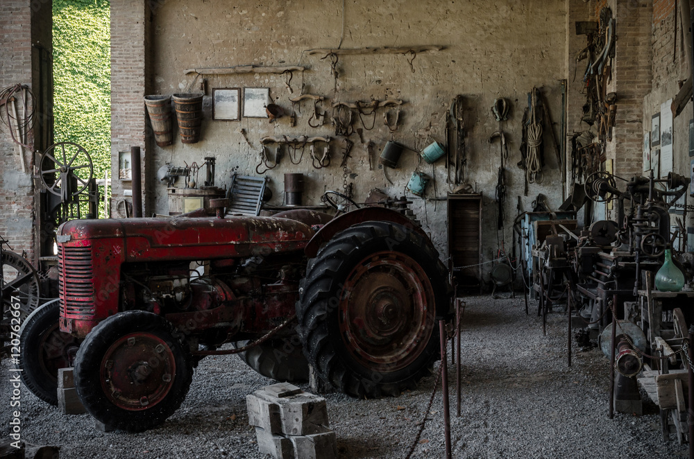 Obraz premium Old tractor in a farmhouse and tools on the wall