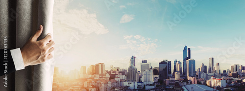 Photography Hand of businessman opening curtain with Bangkok cityscape view in sunrise morni