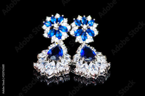 Earrings with blue stones isolated on black, close-up