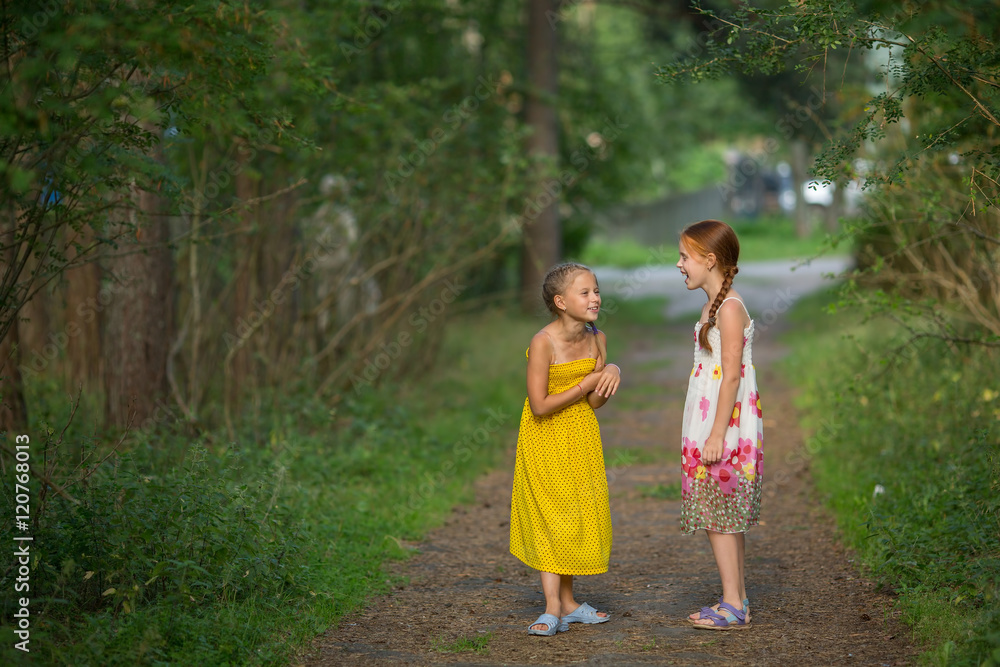 Fototapeta premium Cute little girls excitedly talking in the Park.