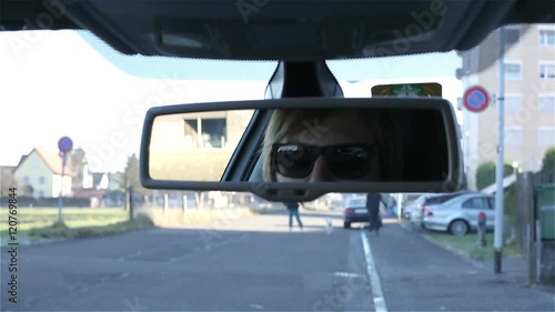 Young attractive man in sunglasses watching car mirror. photo