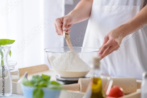 Woman adding powdered yeast to flour