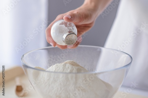 Fotografi Woman adding salt to flour.