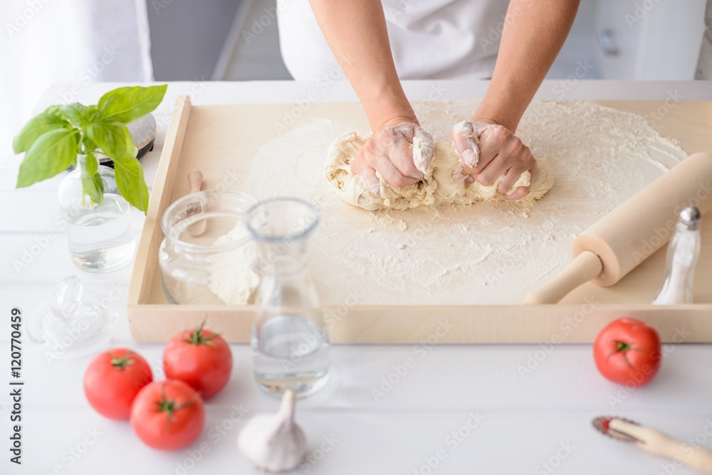 Woman kneading pizza dough on wooden pastry board Woman kneading pizza dough on wooden pastry board