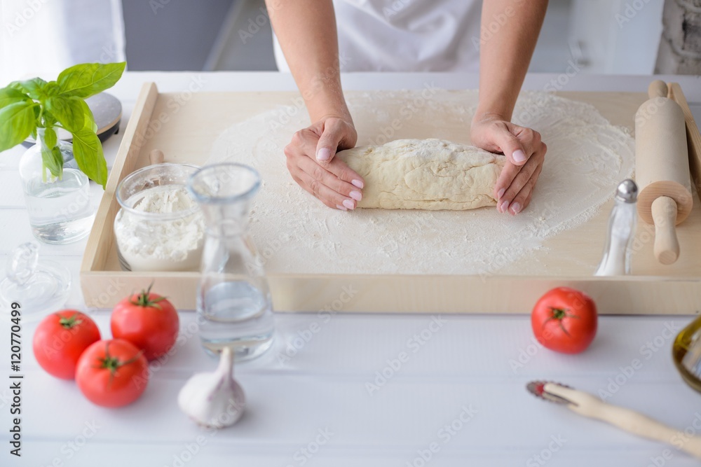 Fototapeta premium Woman kneading pizza dough on wooden pastry board