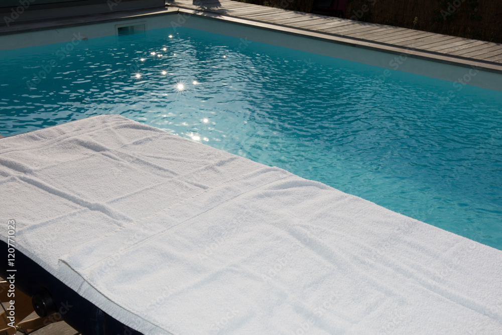 Spa massage table with white towel on swimming pool background