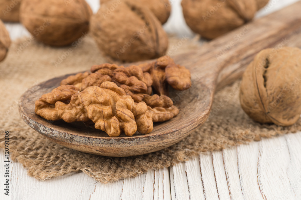 Walnuts in a wooden spoon and an old white wooden table. Walnuts in a wooden spoon and an old white wooden table.