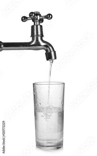 Metal tap with water dripping in glass isolated on white, saving water concept
