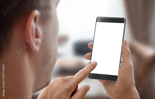 Man hold smartphone in room interior. Left hand touch isolated display for mockup.