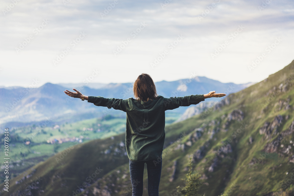 Happy tourist traveler standing on a rock with raised hands, hiker looking to a valley below in trip in spain, hipster young girl enjoying peak of foggy mountain background landscape view mockup
