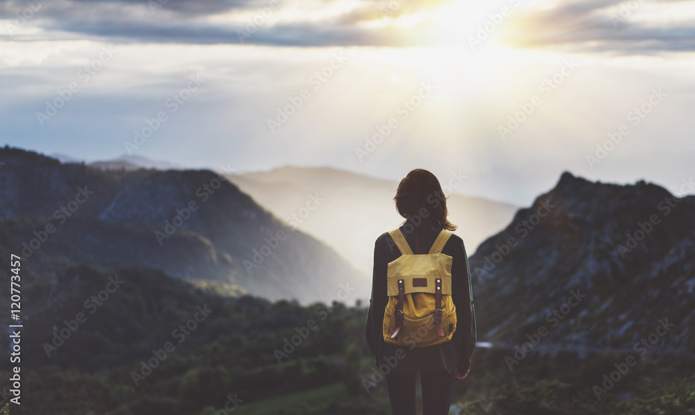 Hipster young girl with bright backpack enjoying sunset on peak of foggy mountain. Tourist traveler on background valley landscape view mockup. Hiker looking sunlight flare in trip in northern spain - obrazy, fototapety, plakaty 