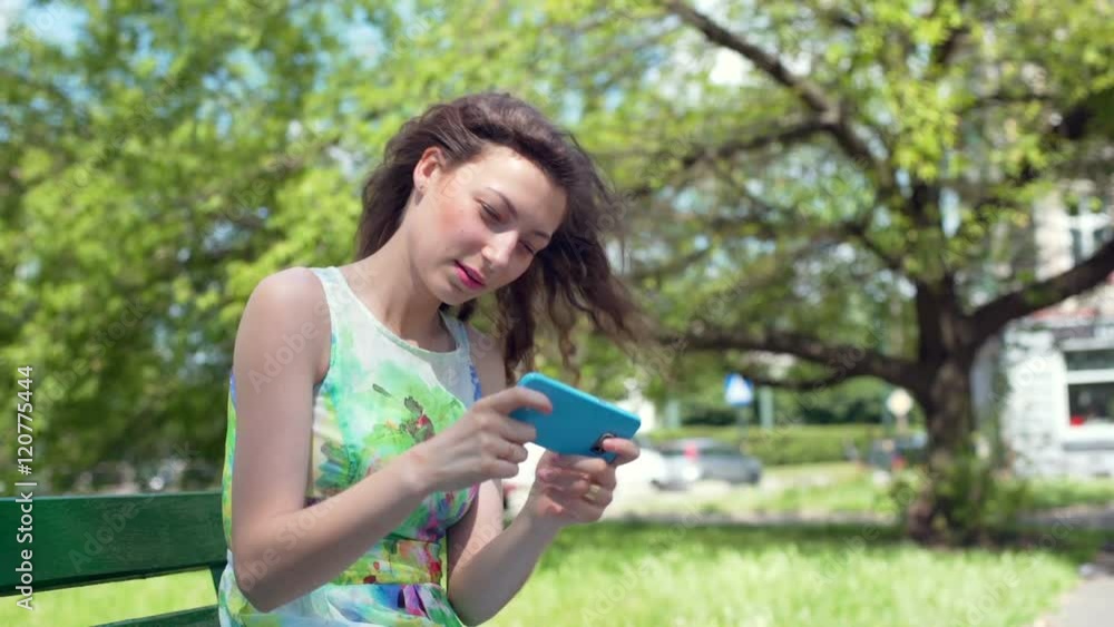 Pretty girl playing a game on smartphone while sitting in the park
Pretty girl playing a game on smartphone while sitting in the park
