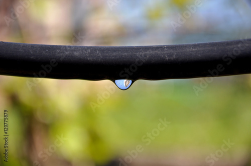 .Drip Irrigation System Close Up. prepared for planting in early Spring. prepared for planting in early Spring. A drop of water on a black hose. Reflection in a drop.