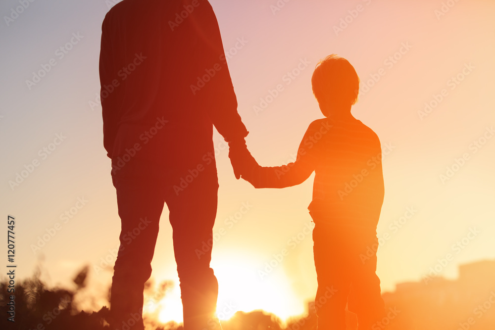 silhouette of father and son holding hands at sunset