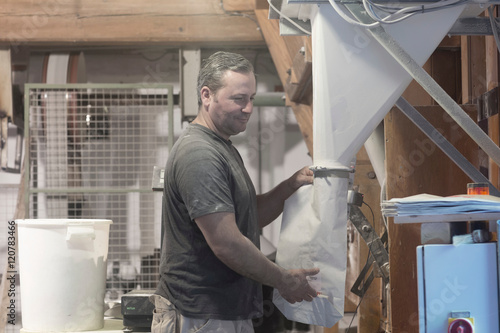 Male miller filling sacks with milled flour in wheat mill
