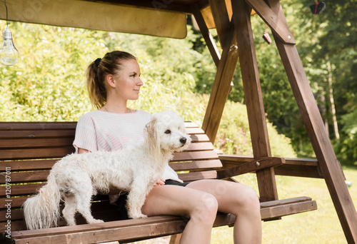 Woman sitting on swingchair with coton de tulear dog, Orivesi, Finland photo