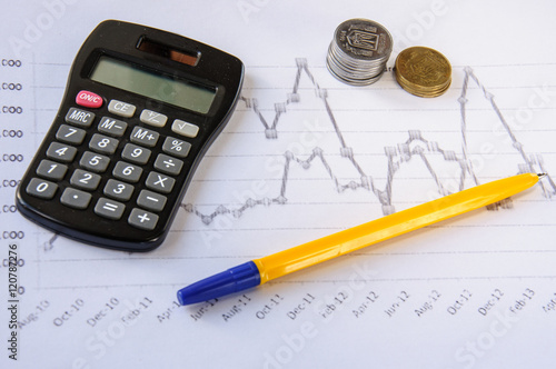 Calculator on the desk pen, calculations, chart, coins