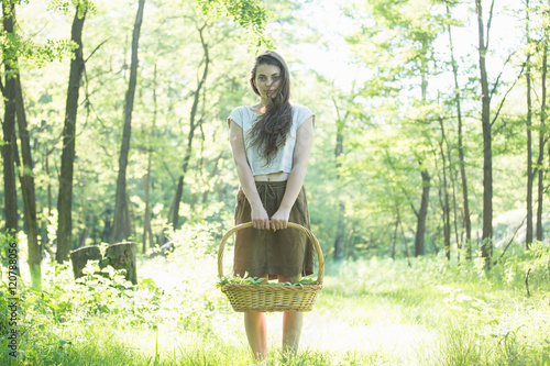 Portrait of young woman foraging wild herbs in forest, Vogogna, Verbania, Piemonte, Italy photo