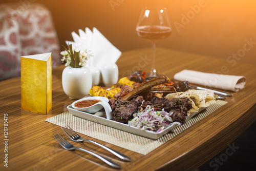 Plate of arabic kebab with potato, tomatoes, pita and wine. photo