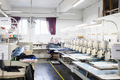 Rows of programmed embroidery machines speed stitching  cloth in clothing factory photo