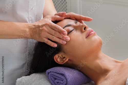 Woman massagist make face lifting massage in spa wellness center photo