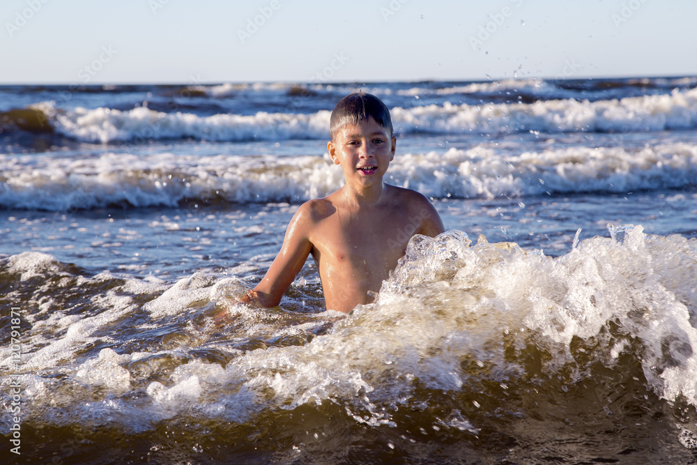 Pretty teenager playing in foamy waves of the Baltic Sea in Jurmala, Latvia