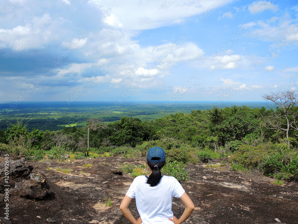 Fototapeta premium Woman looking at beautiful inspirational landscape in high mountains. Young woman enjoying the view on rocky trail top of mountain .