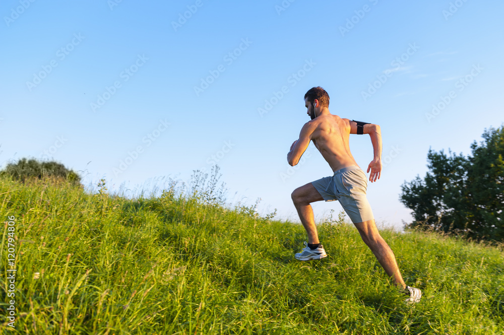 Bare chested man running uphill on meadow Bare chested man running uphill on meadow