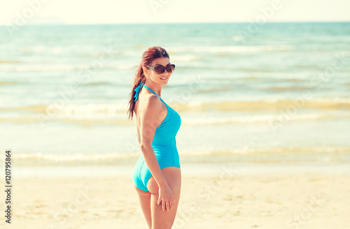 young woman in swimsuit walking on beach