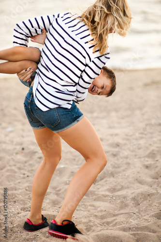 Beautiful woman with a child of four years playing on the beach near the sea