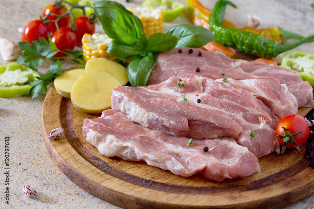 Fresh raw meat pork tenderloin with vegetables on a cutting boar
