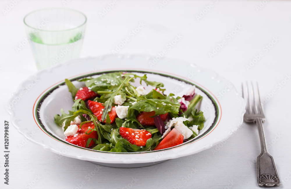 Salad of fresh strawberries,arugula,lettuce,cheese and sesame seeds .healthily cooking concept.selective focus. Salad of fresh strawberries,arugula,lettuce,cheese and sesame seeds .healthily cooking concept.selective focus.