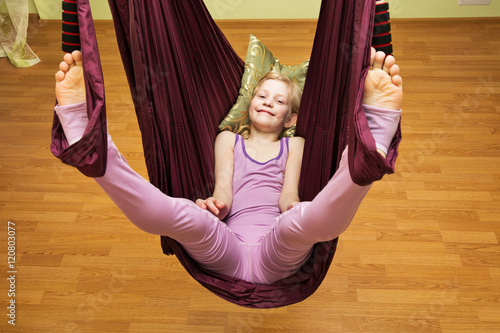 Little girl making aerial yoga exercises, indoor