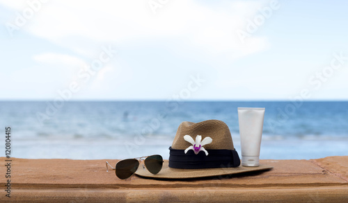 sunglasses and hat and sunblock with flower on the sea