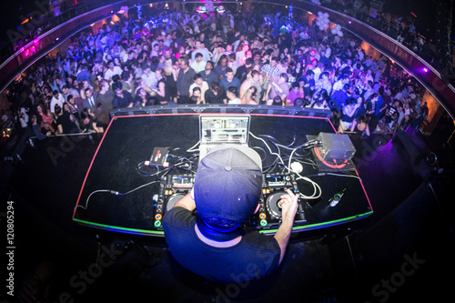 Male DJ performing for crowded nightclub, shot from behind with a fisheye lens