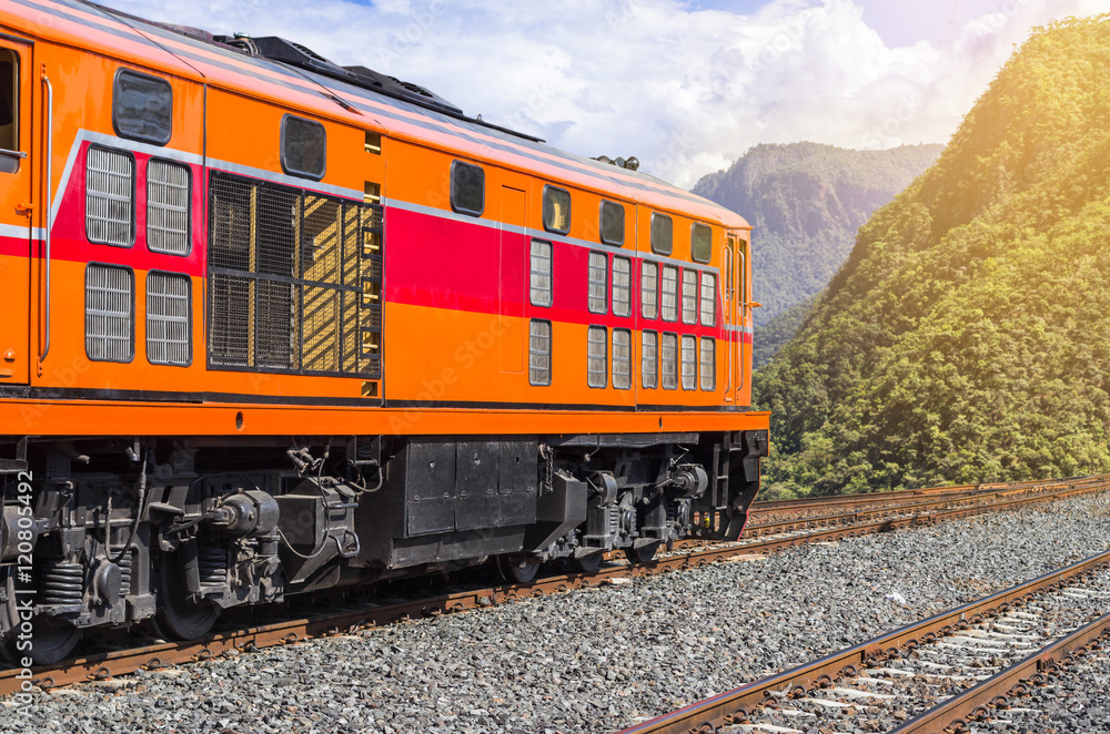 orange diesel engine locomotive passenger train crossing valley mountains  
