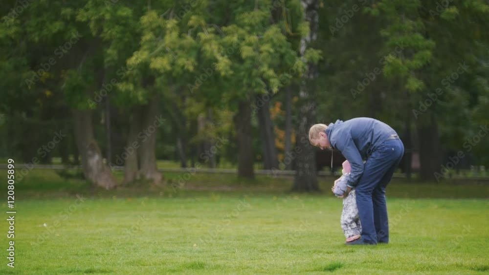 Happy family: Father, Mother and child - little girl walking in autumn park: dad holding daughter Happy family: Father, Mother and child - little girl walking in autumn park: dad holding daughter
