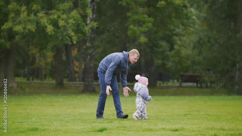 Happy family: Father, Mother and child - little girl walking in autumn park: dad going to the daughter Happy family: Father, Mother and child - little girl walking in autumn park: dad going to the daughter