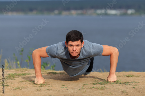 young muscular man doing push-ups outdoors