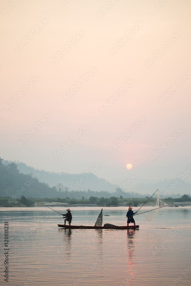 Fisherman on boat with sunrise background, the Mekong River in Thailand.