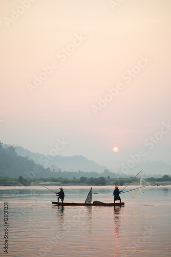 Fisherman on boat with sunrise background  the Mekong River in Thailand.