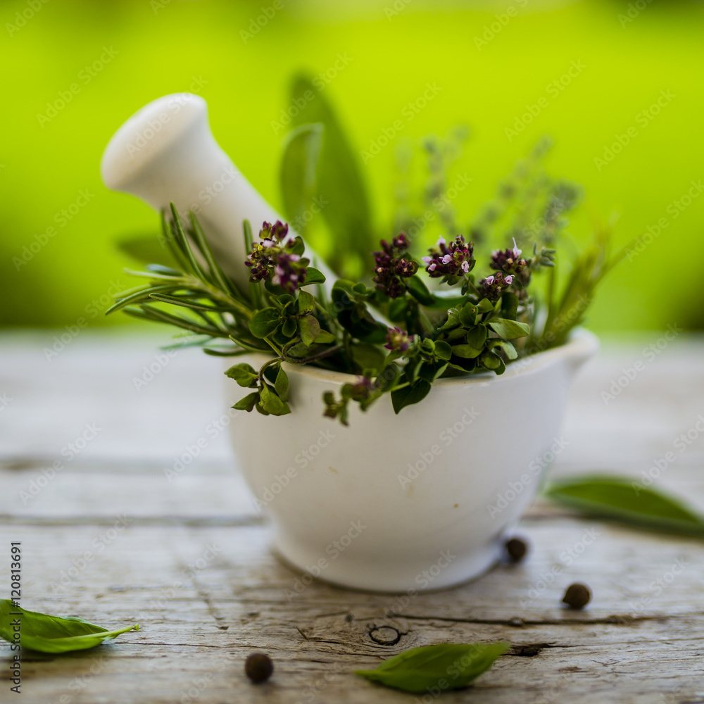 Fresh and aromatic herbs in a mortar on old wooden table.