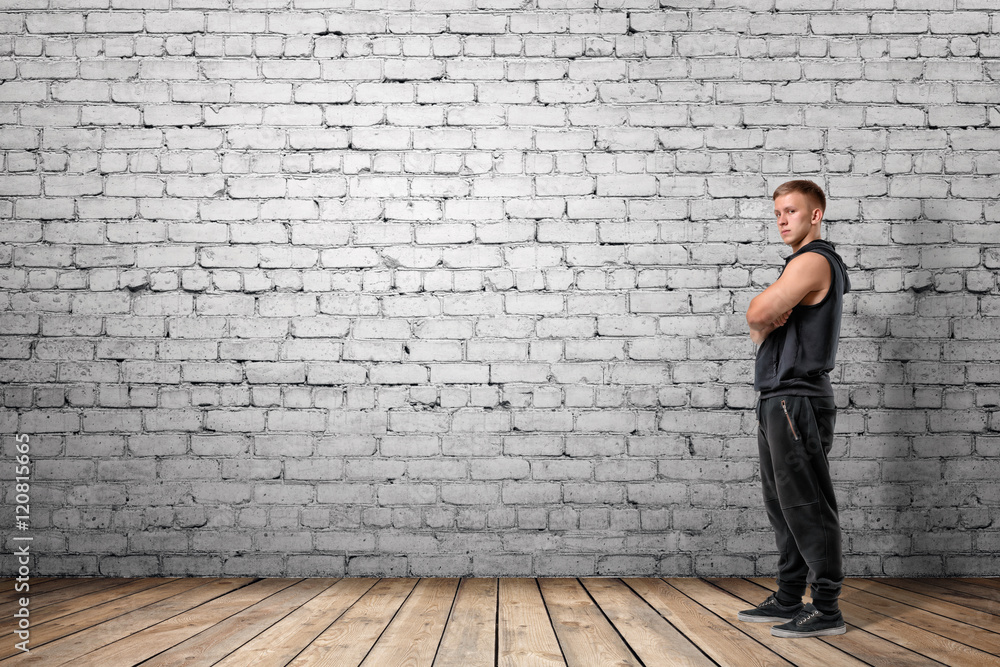 Front view of muscled young man standing with his arms folded looking at the camera Front view of muscled young man standing with his arms folded looking at the camera