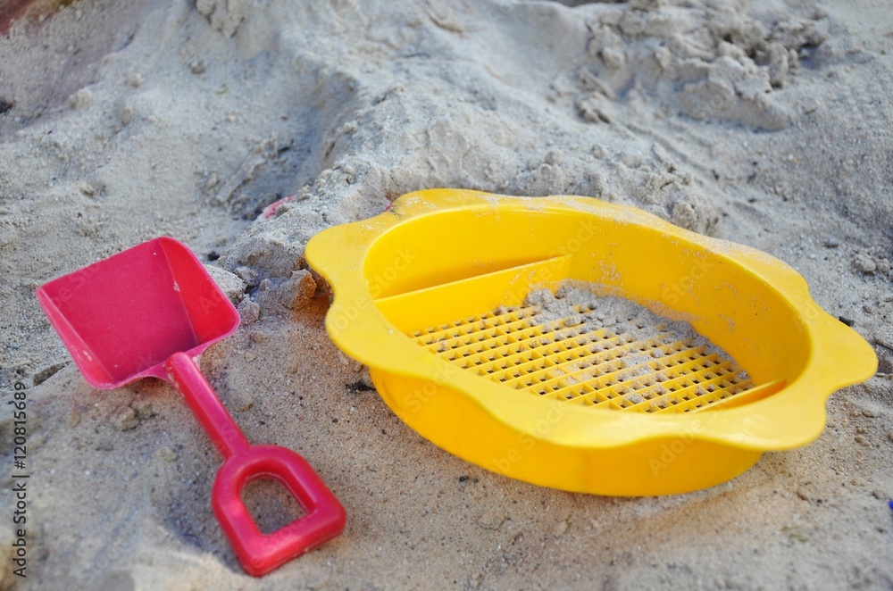 Children plastic strainer and shovel in sandpit