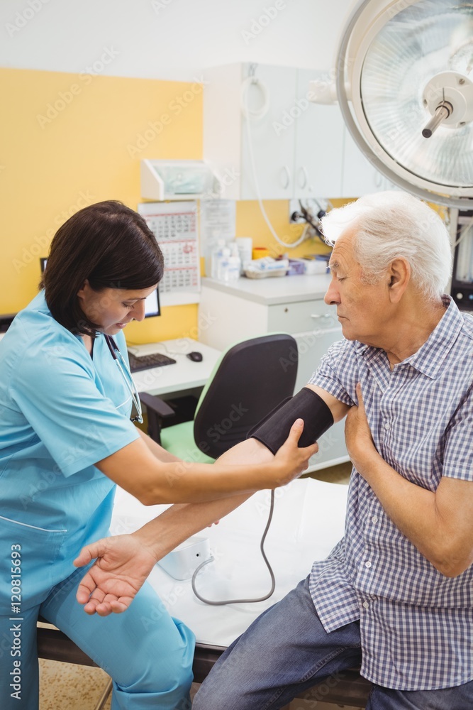 Female doctor checking blood pressure of patient Female doctor checking blood pressure of patient