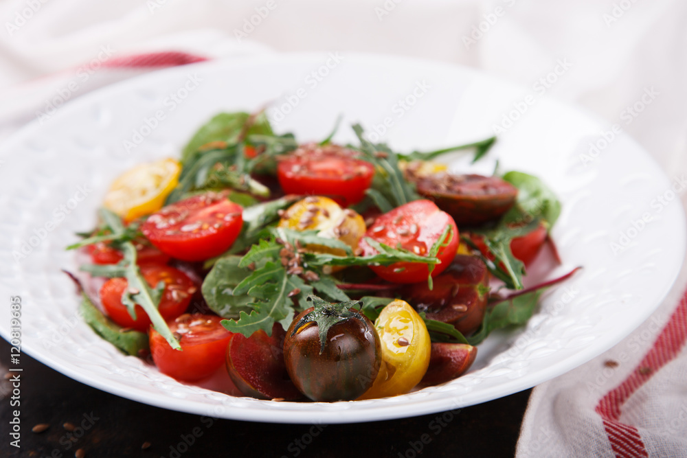 salad of fresh,colored cherry tomatoes with arugula and lemon dressing.selective focus. salad of fresh,colored cherry tomatoes with arugula and lemon dressing.selective focus.