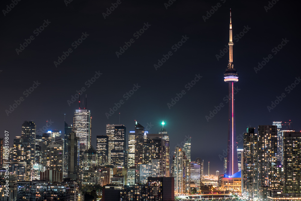 Fototapeta premium Miejski oświetlony krajobraz Toronto. Widok z balkonu na oświetlone ulice, parki, budynki i biurowce w gorącą i wilgotną sierpniową noc w stolicy Ontario w Kanadzie.